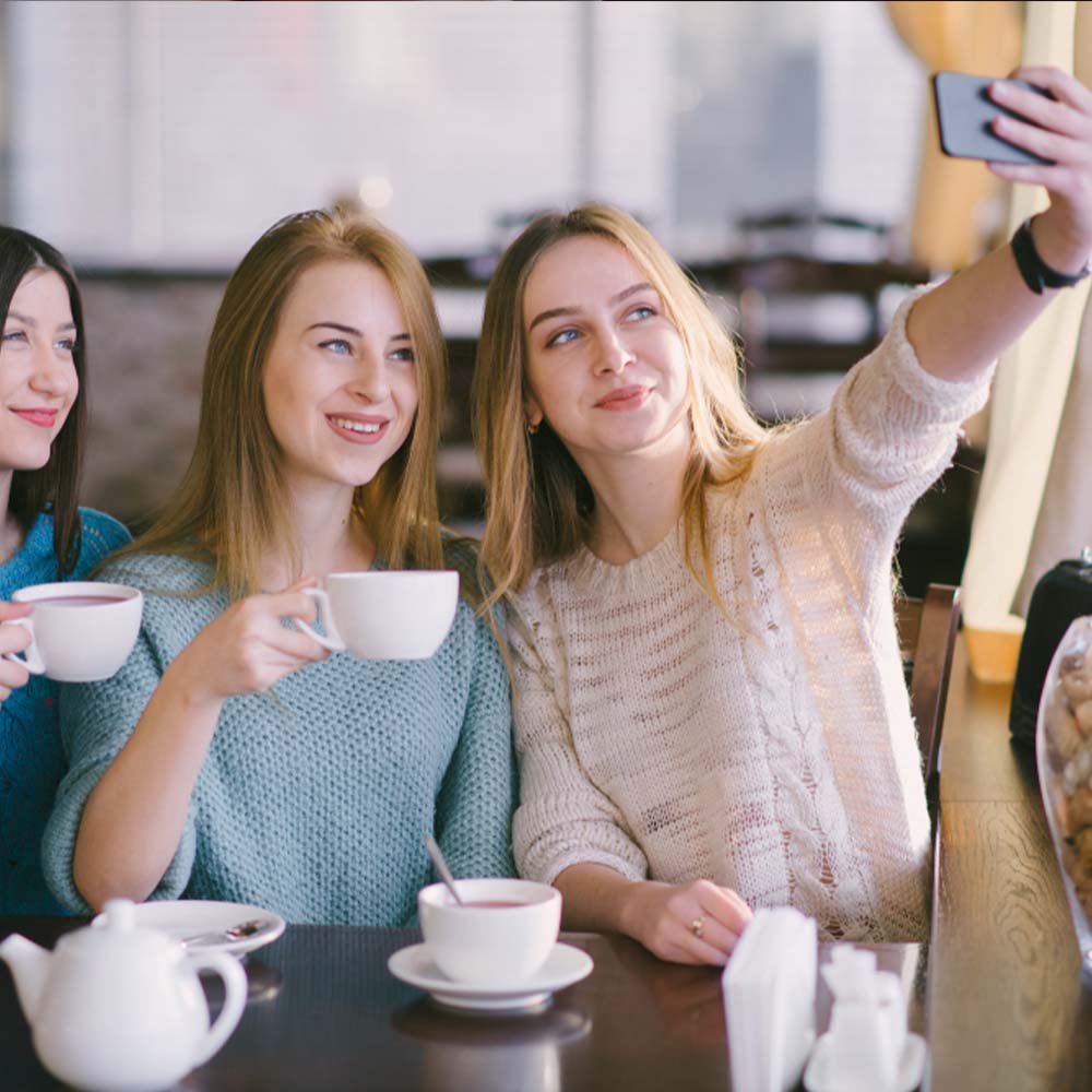 בנות מחזיקות כוס קפה בכנס לעסקים ועושות ספלי