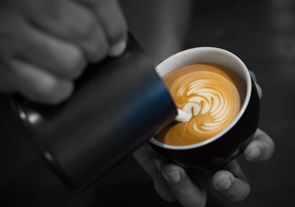 בריסטה מוזג חלב חם לכוס קפה אירוע